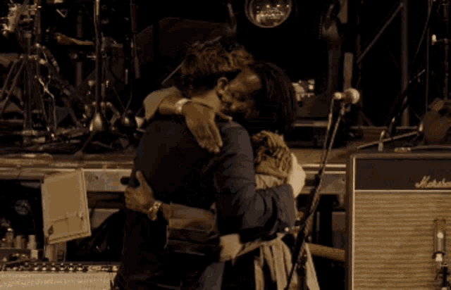 two men hugging on stage in front of a marshall amplifier