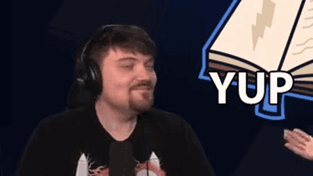 a man wearing headphones is sitting in front of a microphone and talking into it .