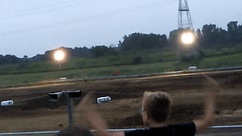 a blurred image of a person watching a race with their arms in the air