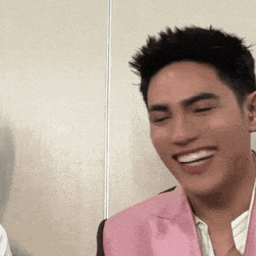 a man wearing a pink jacket is smiling