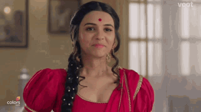 a woman in a red dress with a red dot on her forehead is smiling