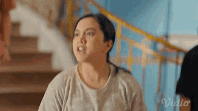 a woman is making a funny face while standing in front of a set of stairs .