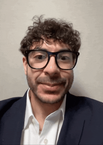 a man with curly hair and glasses is smiling
