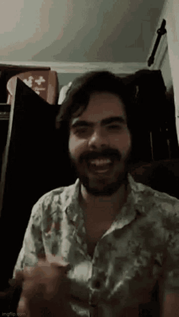 a man with a beard is wearing a floral shirt and smiling .