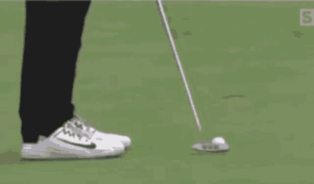 a person is putting a golf ball on a green