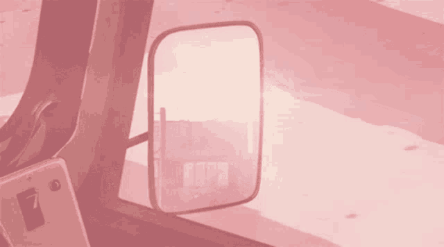 a rear view mirror in a pink car shows a house in the distance
