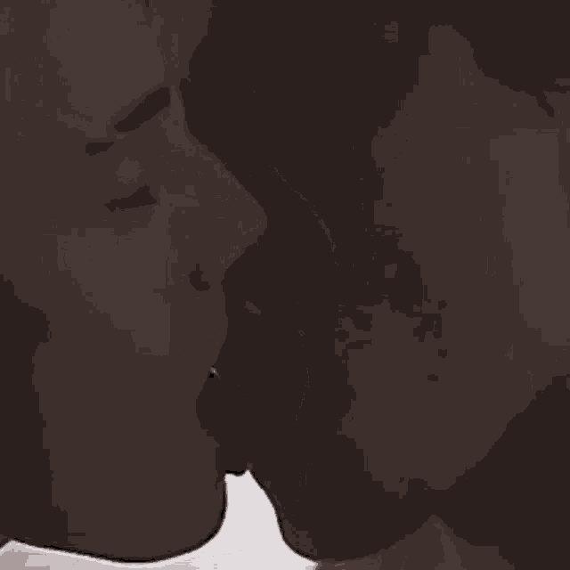 a man and woman are kissing on a bed .