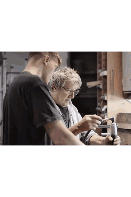 a man and an older man are working together on a piece of metal