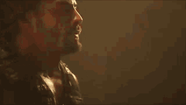 a man with a beard is standing in a dark room and looking down at something .