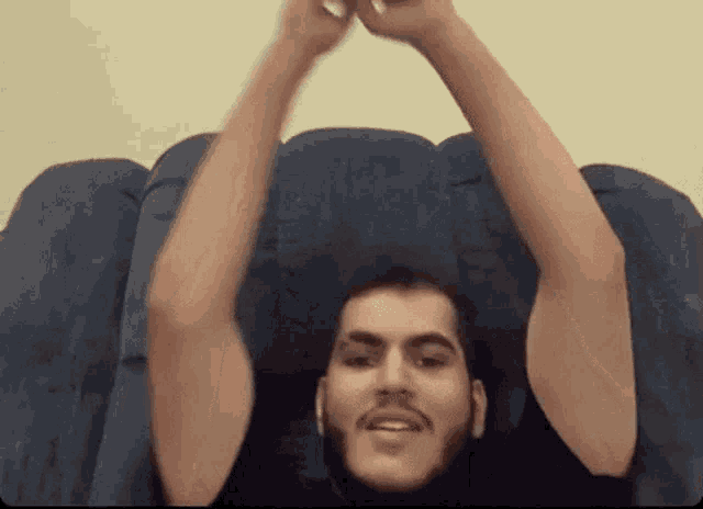 a man is sitting on a couch with his arms in the air .