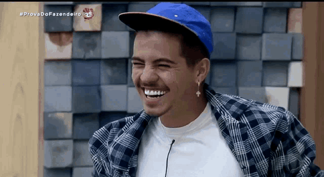a man wearing a plaid shirt and a blue hat laughs