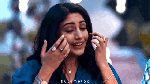 a woman in a blue shirt is covering her face with her hands and the words kutumotox are on the bottom right