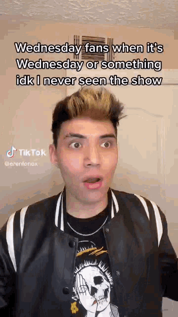 a man is making a funny face while wearing a black and white jacket and a skull t-shirt .