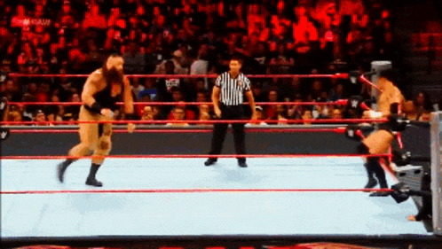 two wrestlers are fighting in a ring with a referee in the background
