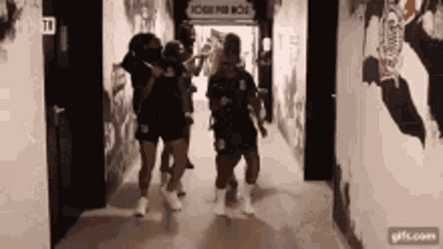 a group of people are walking down a hallway with a sign on the wall that says home per noi .