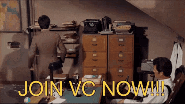 a man is sitting at a desk with the words join vc now