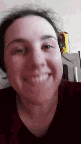 a close up of a woman 's face smiling with a yellow item in the background