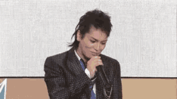 a man in a suit and tie is holding a microphone in front of his face .