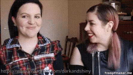 two women are standing next to each other and smiling at each other .