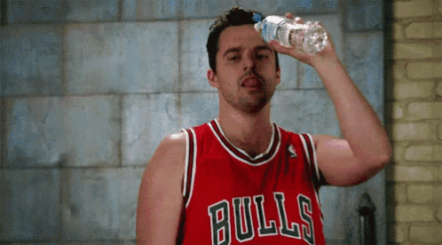 a man wearing a bulls jersey is drinking water