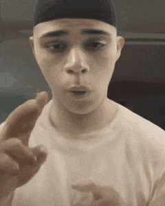 a man wearing a white shirt and a black hat is pointing his finger