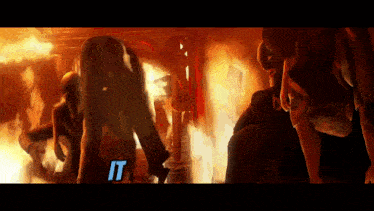 a group of people standing in front of a fire with the word " it " on the bottom right