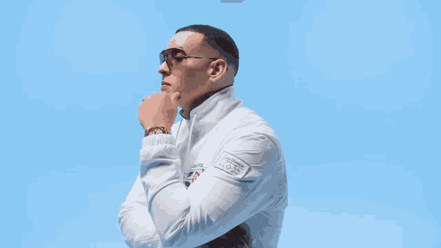 a man wearing sunglasses and a white jacket with a patch on the sleeve that says ' longines '
