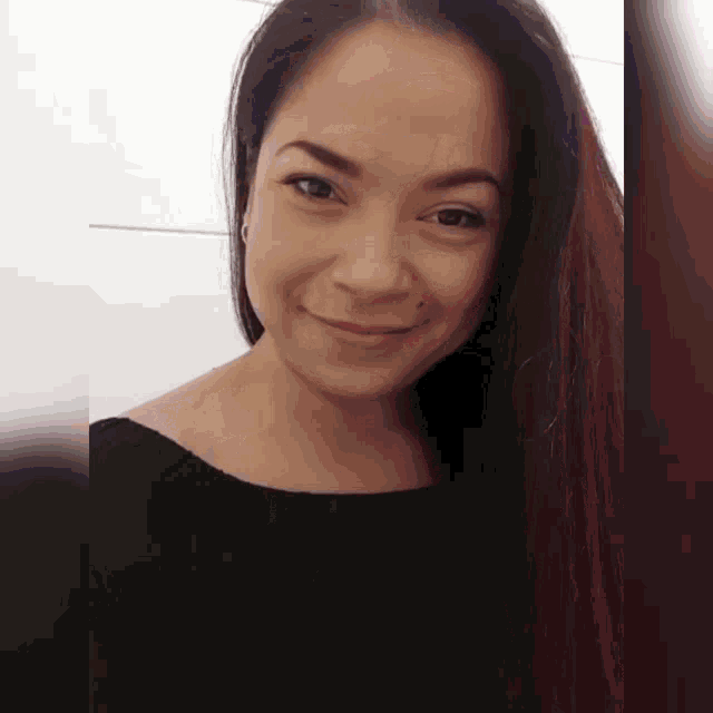 a woman with long hair is smiling and wearing a black top