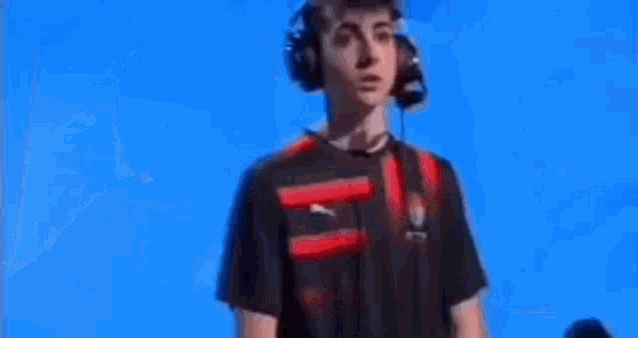 a man wearing headphones and a red and black shirt is sitting in front of a blue background .