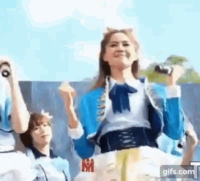a woman in a blue jacket is singing into a microphone while dancing on a stage .