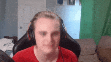 a man wearing headphones and a red shirt is looking at the camera