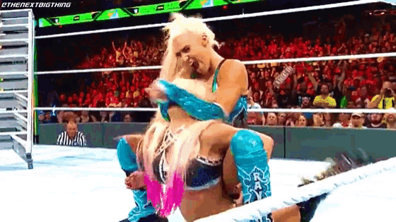 a female wrestler is carrying another wrestler on her shoulders in a wrestling ring .