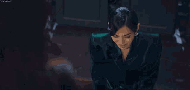 a woman in a green dress is kneeling in a dark room