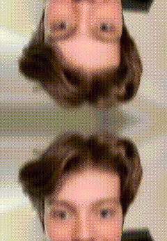 a man is taking a selfie in front of a mirror with his head upside down .