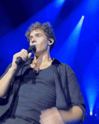 a man is singing into a microphone on a stage