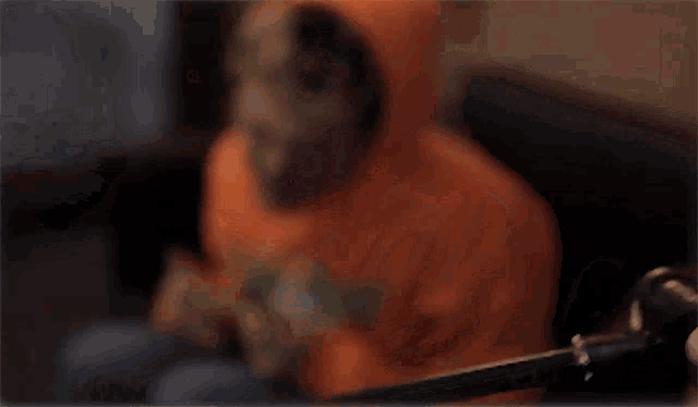 a man wearing an orange hoodie has a white sticker on his chest