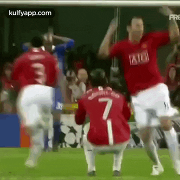a group of soccer players are celebrating a goal on a field . one of the players has the number 7 on his shirt .