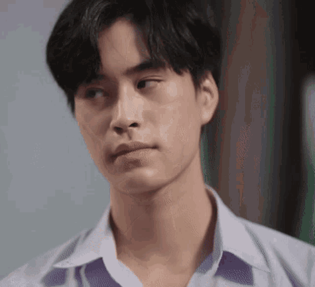 a close up of a young man 's face in a white shirt looking at the camera .