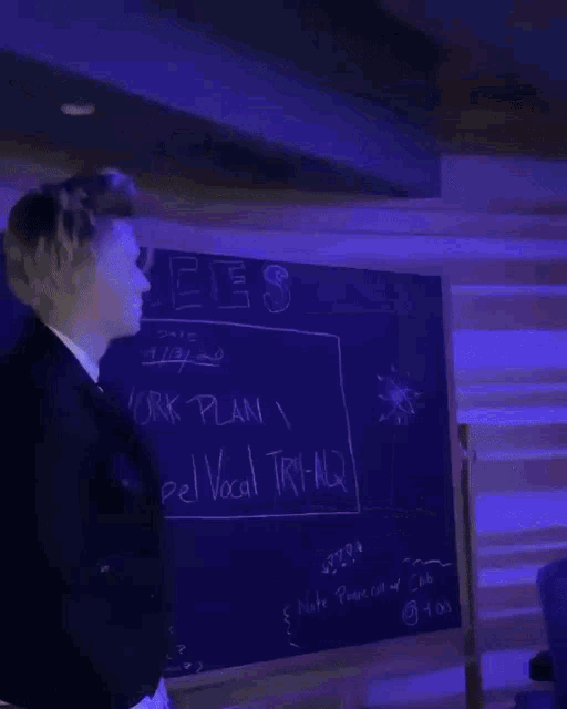 a man in a black jacket is standing in front of a blue light