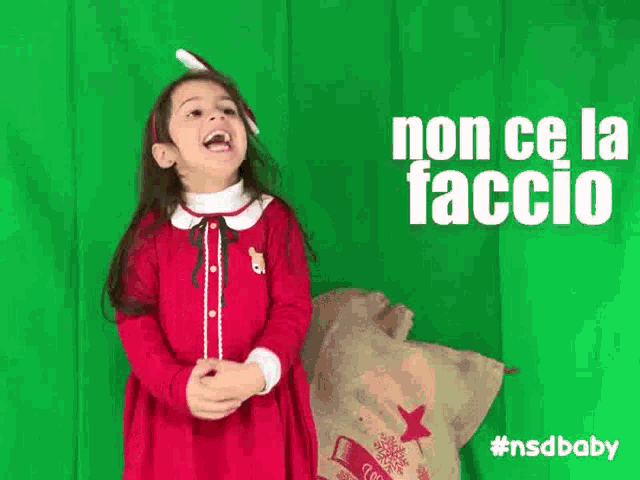 a little girl in a red dress stands in front of a green screen with the words non ce la faccio written on it