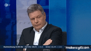 a man in a suit is sitting in front of a screen that says make a gif.com on it