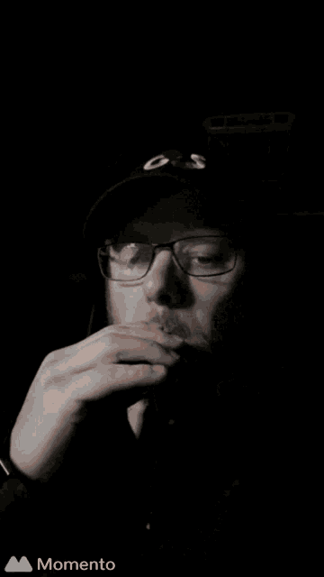 a man with glasses and a beard is blowing smoke out of his mouth and the word momento is on the bottom