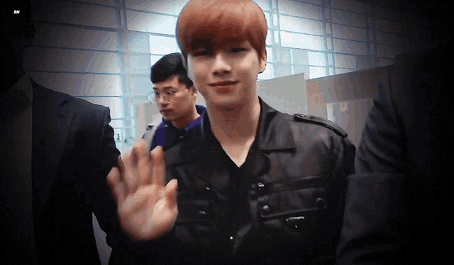 a man in a black jacket is waving at someone