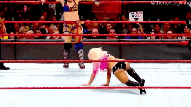 two women are wrestling in a ring with a sign that says i 'm a live queen on it .