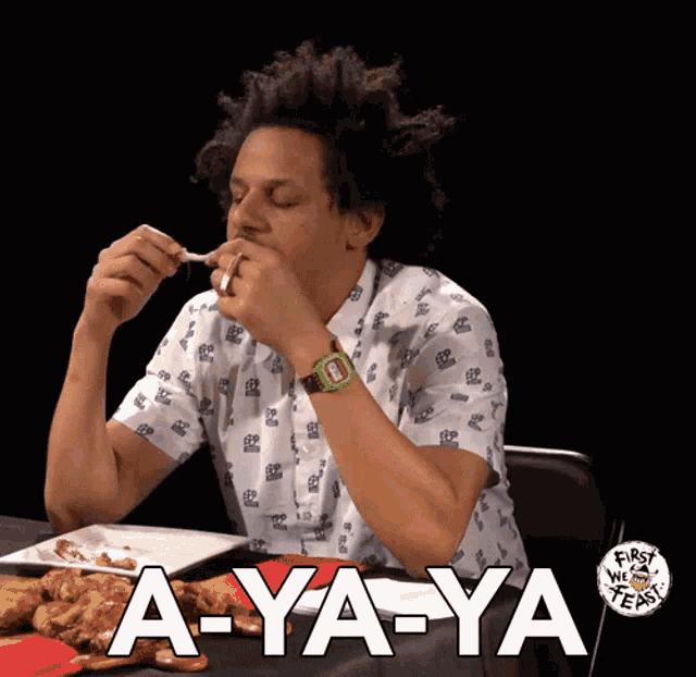 a man sitting at a table with a plate of food and a sign that says a-ya-ya on it