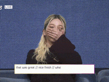 a woman covering her face with her hand with a live sign in the background