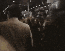a man in a suit and tie stands in a crowd of people