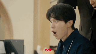 a man is making a funny face while looking at a laptop .