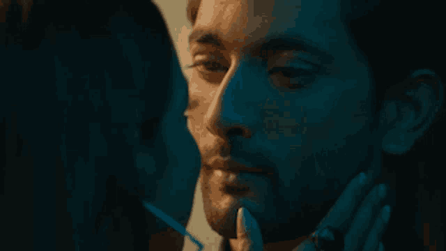 a woman is touching a man 's face with her finger