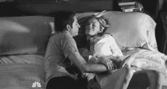 a man and a woman are laying on a bed and kissing .